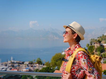 female summer travel to Antalya, Turkey. young asian woman in red dress walk through old town Kalechi , Panoramic view of Antalya Old Town port, Taurus mountains and Mediterrranean Sea, Turkeyの写真素材