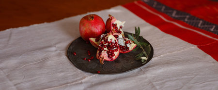 Image of Still Life with Turkish Pomegranate and olive branch on old retro plate. Dark wood background, antique copper plate. Fresh ripe whole pomegranates, opened pomegranate and seedsの写真素材