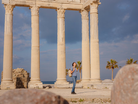 travel to ancient city of Side, Antalya coast of Turkey in tourist low season. Young tourist Asian woman is posing in front of temple of Apolloの写真素材