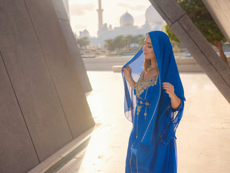 Travel to the United Arab Emirates, Abu Dhabi. Woman in blue Arabic dress near Sheikh Zayed Great white mosque. famous Abu Dhabi sightseeing.の写真素材
