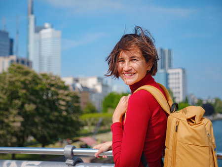Tourist woman explores modern Frankfurt, walking through vibrant streets with contemporary architecture, skyscrapers, and urban spaces, enjoying lively atmosphere of modern side.の写真素材