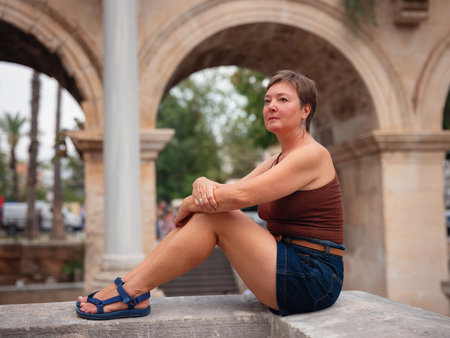 Woman walking narrow streets of old town Antalya during warm summer evening. Historic atmosphere and Mediterranean charm creates peaceful travel experience. at Hadrian's Gate in Antalya Turkey.の写真素材