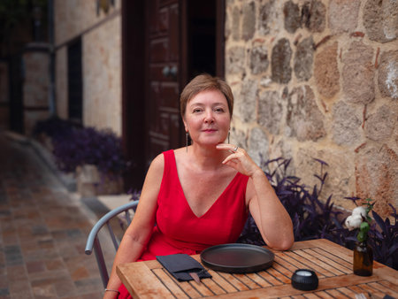 Woman in red dress walking narrow streets of old town Antalya during warm summer evening. Historic atmosphere and Mediterranean charm creates peaceful travel experience.の写真素材