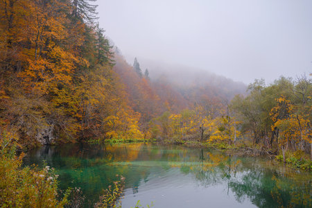 Plitvice Lakes in Croatia during autumn, showcasing stunning waterfalls, vibrant foliage, and crystal-clear waters, creating a magical and serene natural landscape. Lake fog with Autumn foliageの写真素材