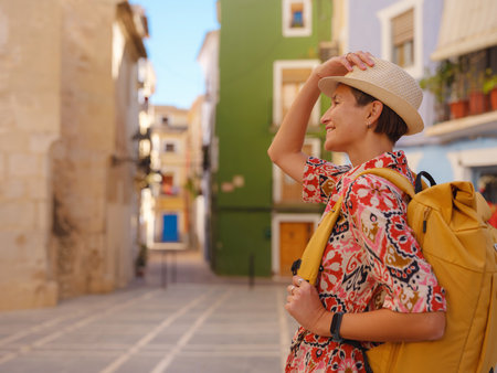 Woman in dress strolls through colorful streets of Spanish coastal town of La Vila Joiosa or Villajoyosa. sunny winter highlights atmosphere charm of Mediterranean architecture and quiet seaside lifeの写真素材