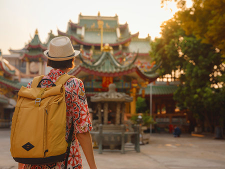 Woman Exploring Colorful Streets Near Buddhist Temples in Bangkok. Female traveler strolling through charming streets of Bangkok, surrounded by traditional architecture and beautiful Buddhist temples.の写真素材