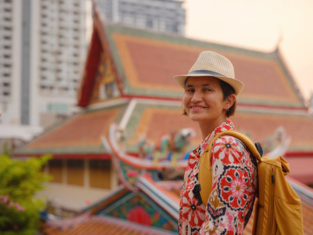 Woman Exploring Colorful Streets Near Buddhist Temples in Bangkok. Female traveler strolling through charming streets of Bangkok, surrounded by traditional architecture and beautiful Buddhist temples.の写真素材