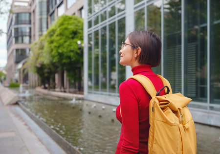 Tourist woman explores modern Frankfurt, walking through vibrant streets with contemporary...