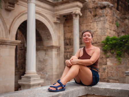 Woman walking narrow streets of old town Antalya during warm summer evening. Historic atmosphere and Mediterranean charm creates peaceful travel experience. at Hadrian's Gate in Antalya Turkey.の写真素材
