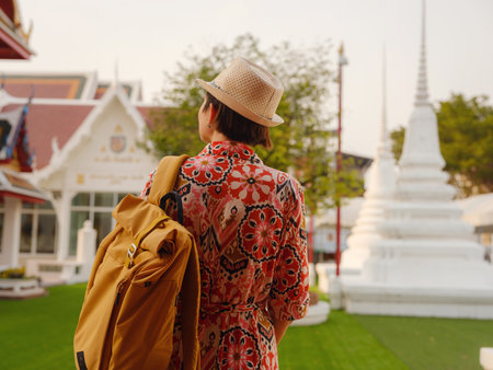 Woman Exploring Colorful Streets Near Buddhist Temples in Bangkok. Female traveler strolling through charming streets of Bangkok, surrounded by traditional architecture and beautiful Buddhist temples.の写真素材