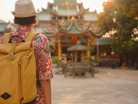 Woman Exploring Colorful Streets Near Buddhist Temples in Bangkok. Female traveler strolling through charming streets of Bangkok, surrounded by traditional architecture and beautiful Buddhist temples.の写真素材