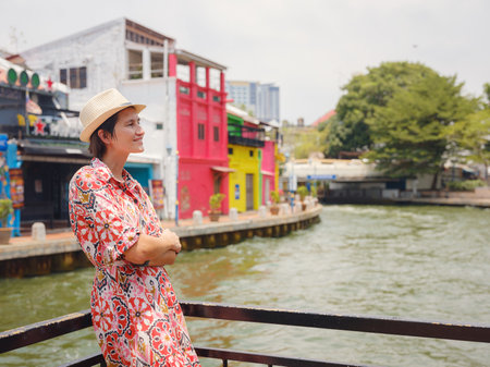 Young woman in ethnic dress and hat exploring the vibrant streets of Malacca, Malaysia. A blend of cultural heritage, colorful architecture, and tropical charm. Perfect travel and lifestyle moments.の写真素材