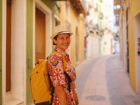 Woman in dress strolls through colorful streets of Spanish coastal town of La Vila Joiosa or Villajoyosa. sunny winter highlights atmosphere charm of Mediterranean architecture and quiet seaside lifeの写真素材
