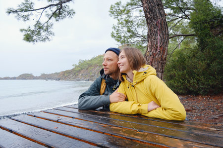 Couple enjoys Turkish coastline. walking in stone beach, watching sea waves, relaxing together, slow romantic moment near calm blue water under soft winter light.の写真素材
