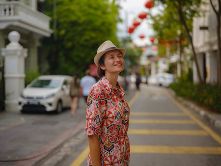 Young woman in ethnic dress and hat exploring festive streets of George Town, Malaysia, during Chinese New Year. Vibrant lanterns, cultural celebrations, historic charm create unique atmosphere.の写真素材