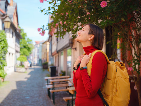 Tourist woman enjoys historic charm of Hochst near Frankfurt, wandering through picturesque streets with old houses and cobblestone alleys, soaking in peaceful atmosphere of old town.の写真素材