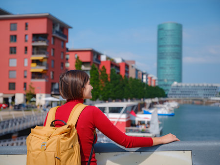Tourist woman explores modern Frankfurt, walking through vibrant streets with contemporary architecture, skyscrapers, and urban spaces, enjoying lively atmosphere of modern side.の写真素材