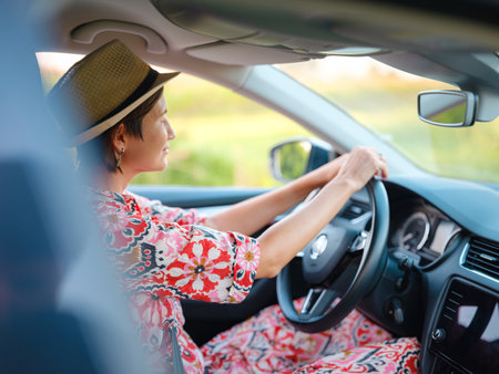 Young woman drives through scenic countryside, hands on wheel, focused on road ahead. Peaceful summer journey through rural landscapes captures freedom and adventure. Croatia, Europeの写真素材