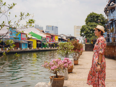 Young woman in ethnic dress and hat exploring the vibrant streets of Malacca, Malaysia. A blend of cultural heritage, colorful architecture, and tropical charm. Perfect travel and lifestyle moments.の写真素材