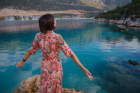 Woman stands on Mediterranean Sea coast, embracing cool, off-season atmosphere with waves crashing on shore and overcast sky above. serene, peaceful moment on quiet beach.の写真素材