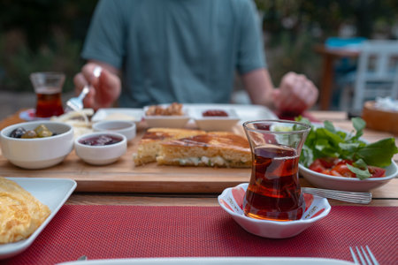 Traditional Turkish breakfast spread with fresh bread, olives, cheese, tomatoes, cucumbers, and variety of jams and spreads. Enjoyed in vibrant setting, capturing essence of Turkish morning culture.の写真素材