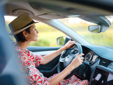 Young woman drives through scenic countryside, hands on wheel, focused on road ahead. Peaceful summer journey through rural landscapes captures freedom and adventure. Croatia, Europeの写真素材