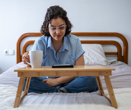 Woman enjoys reading an e-book on bedの写真素材