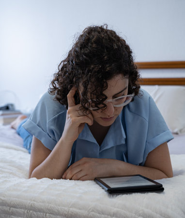 Beautiful woman reads an E-Book on bedの写真素材