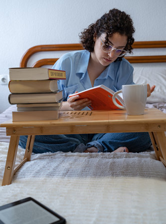 Woman surrounded by books and an e-bookの写真素材