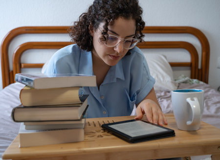 Woman with glasses reads an e-book on a coffee table front viewの写真素材