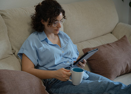 Woman reading an e-book with a mug of coffeeの写真素材