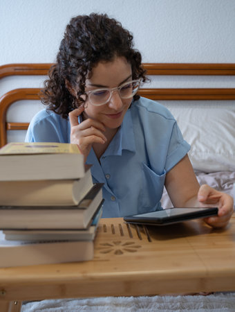 Woman with glasses reads an e-book on a coffee table front viewの写真素材