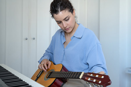 Beautiful woman playing the guitar at homeの写真素材