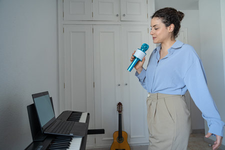 Woman singing with a microphone in front of a laptopの写真素材