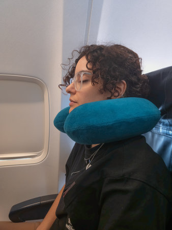 Pretty woman sleeping on seat plane with neck cushionの写真素材