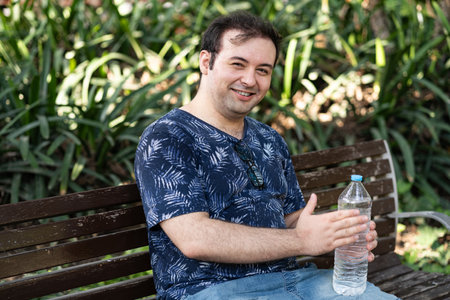 Young man laughing with bottle of waterの写真素材
