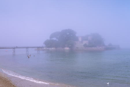 Beautiful view of bridge to amazing island fortress on foggy day near seaの写真素材