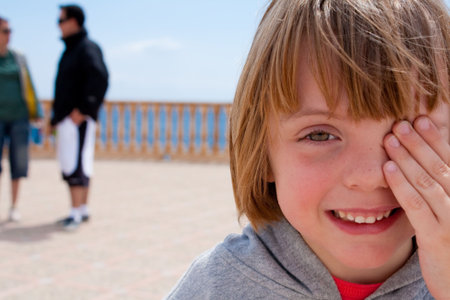 girl smiling, hand over eye, blurred backgroundの写真素材