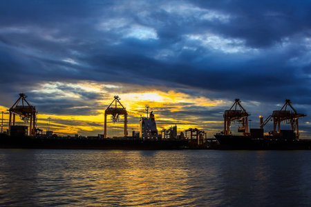 Container Cargo freight ship with working crane bridge in shipyard at twilighの写真素材