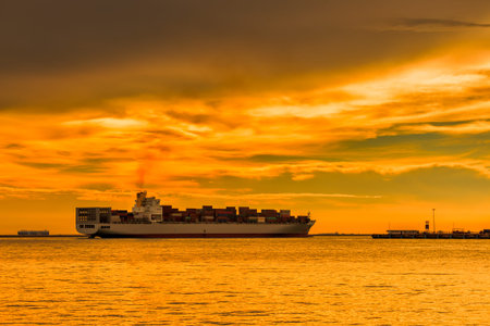 cargo container ship at mediterranean coast in sunsetの写真素材