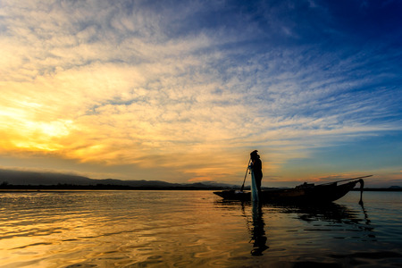Fishermen on boat fishing at lake in Thailandの写真素材