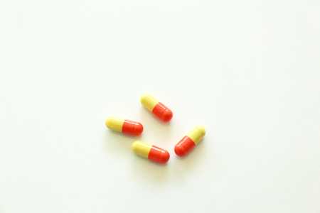 Yellow-red capsules. Some capsules and pills isolated on white backgroundの写真素材
