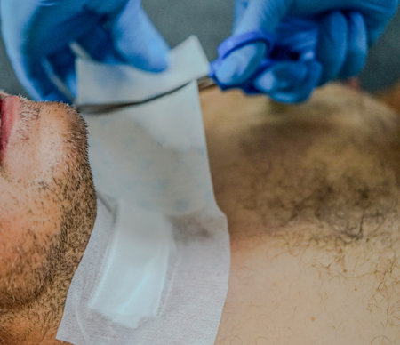 Close-up of a man's face being cut by a beautician