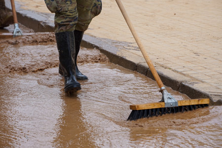 Worker cleans the road from the mud with a shovel in the cityの写真素材