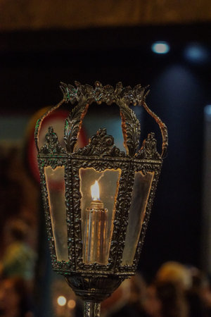 An ornate antique lantern with a lit candle inside, featuring decorative metalwork and glass panelsの写真素材