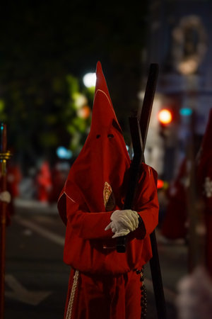 Nazarenes in red, processioning through the streets of Murcia, on Holy Wednesday, with their hats...