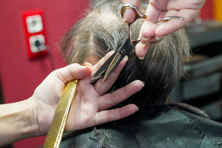 Hairdresser cuts hair of a woman in a beauty salon