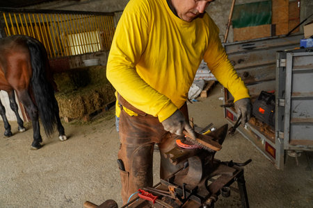 Farrier brushing a glowing horseshoe to remove impurities, working on an anvil