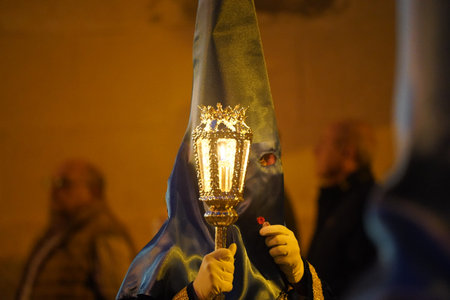 traditional Nazarene of Holy Week in Spain, carrying a candlestick, with a lit candle inside