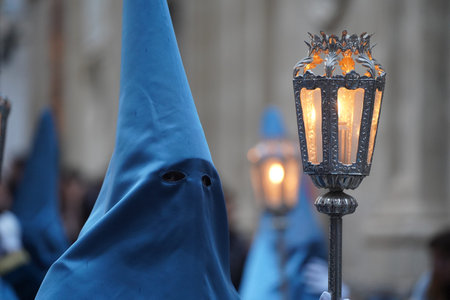 A blue Nazarene, with a lantern and a candle inside, stands through the streets of a Spanish city.